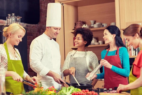 Glückliche Frauen und Koch kochen in der Küche — Stockfoto