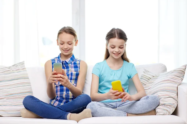 Chicas felices con teléfonos inteligentes sentados en el sofá —  Fotos de Stock