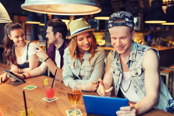 Gelukkige vrienden met tablet pc en drankjes in bar — Stockfoto
