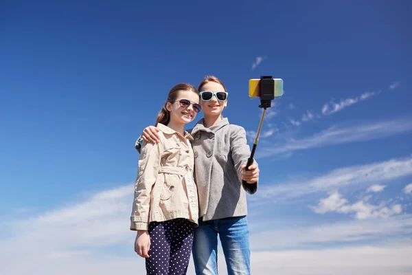 Happy girls with smartphone selfie stick — Stock Photo, Image