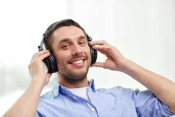 Glimlachende jongeman in hoofdtelefoon thuis — Stockfoto