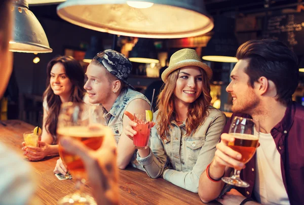 Amigos felizes com bebidas conversando no bar ou pub — Fotografia de Stock