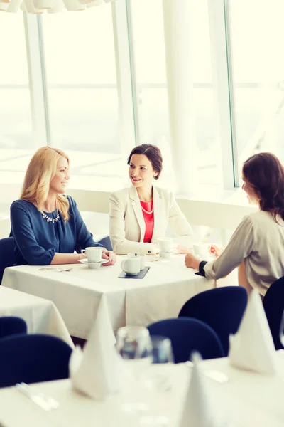 Women drinking coffee and talking at restaurant — Stock Photo, Image