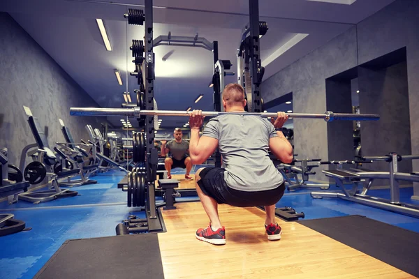 Ung man böjning muskler med bar i gymmet — Stockfoto