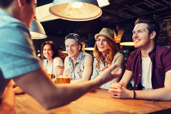 Glada vänner dricker öl och pratar på bar — Stockfoto