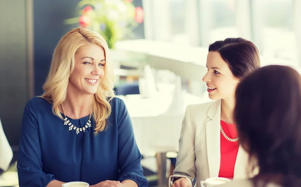 Women drinking coffee and talking at restaurant — Stock Photo, Image