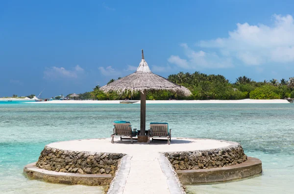 Palapa en ligbedden door zee op Malediven strand — Stockfoto