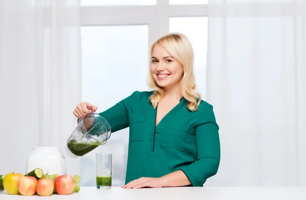 Happy woman with blender jug pouring juice at home — Stock Photo, Image