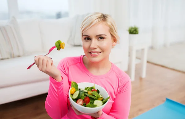 Lachende jonge vrouw salade eten thuis — Stockfoto