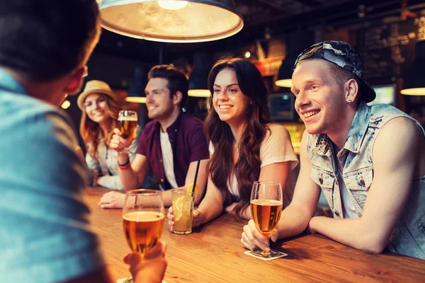 Amigos felices con bebidas hablando en el bar o pub — Foto de Stock