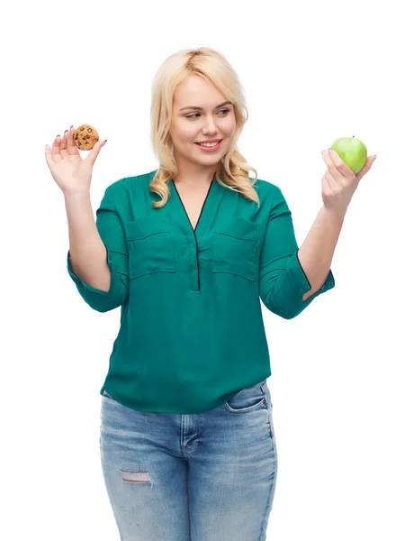 Femme souriante choisir entre pomme et biscuit — Photo