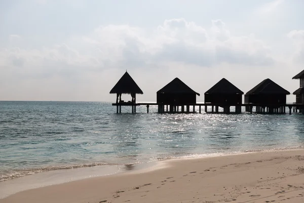 Bungalow huts i havsvatten på exotiska resort beach Stockbild