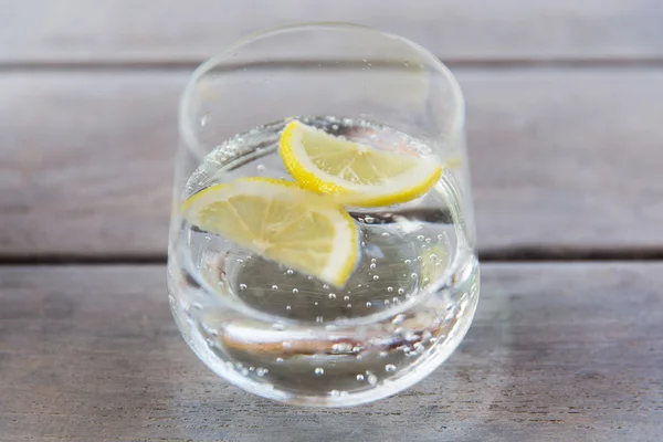 テーブルの上にレモンと輝く水のガラス — ストック写真