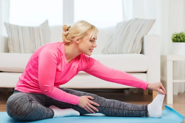 Happy woman stretching leg on mat at home — Stock Photo, Image