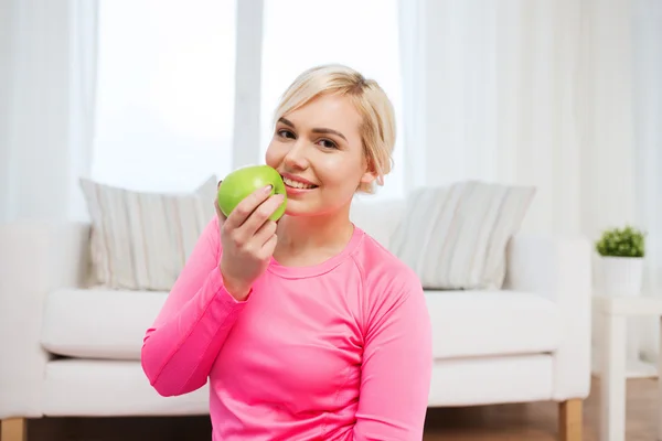 Lycklig kvinna äta äpple hemma — Stockfoto