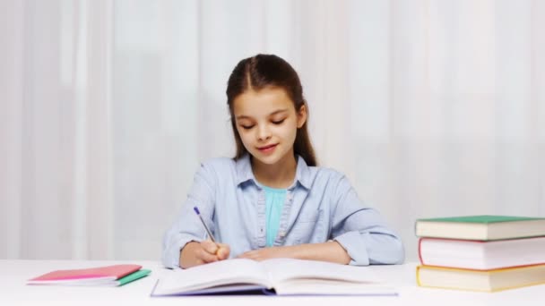 Menina da escola escrevendo tarefa matemática para bloco de notas — Vídeo de Stock