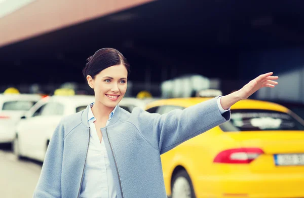 Lächelnde junge Frau winkt mit der Hand und fängt Taxi — Stockfoto