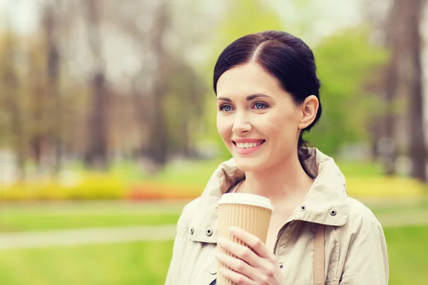 Leende kvinna dricka kaffe i park — Stockfoto