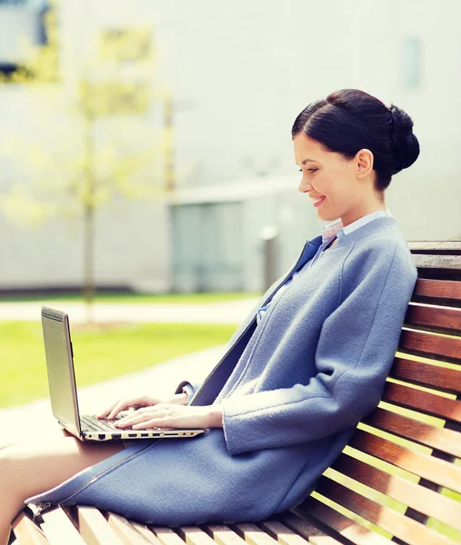 Uśmiechnięta kobieta biznesu z laptopa w mieście — Zdjęcie stockowe