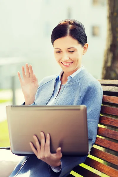 Glimlachende zakenvrouw met laptop in stad — Stockfoto