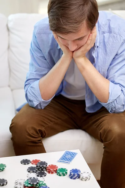 Homem com cartas de jogo e fichas em casa — Fotografia de Stock