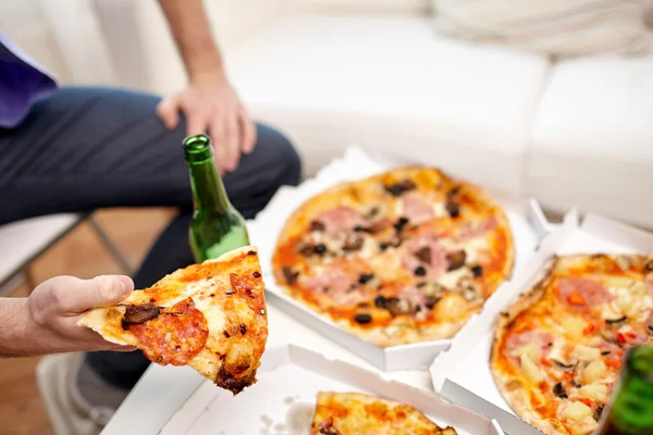 Nahaufnahme eines Mannes, der zu Hause Pizza mit Bier isst — Stockfoto