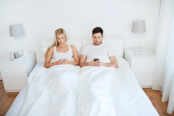 Couple avec smartphones au lit — Photo