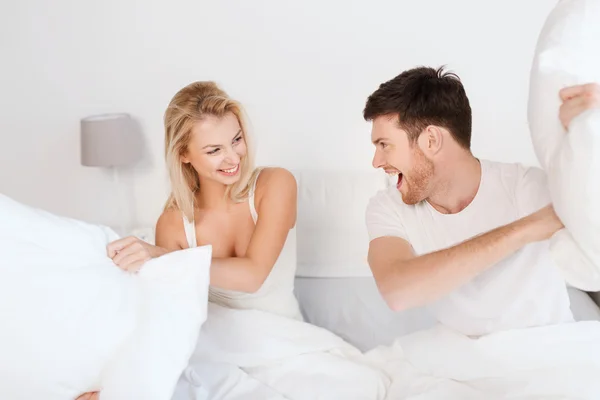 Casal feliz ter travesseiro luta na cama em casa Imagem De Stock