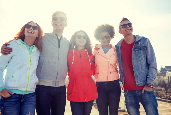 Happy teenage friends in shades hugging on street — Stock Photo, Image