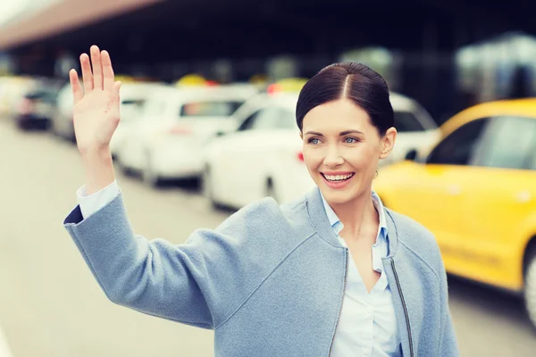 Sonriente joven con la mano agitada sobre el taxi — Foto de Stock