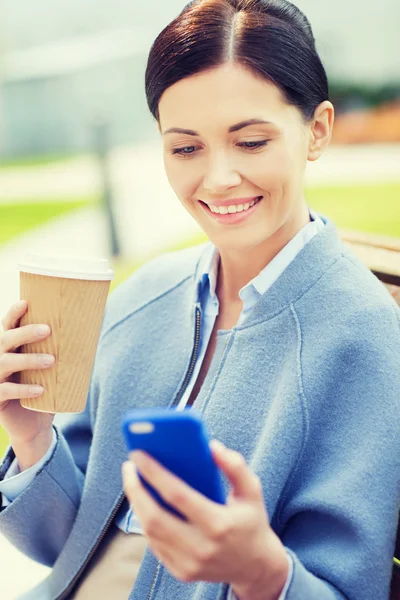 Lachende vrouw met koffie en smartphone — Stockfoto