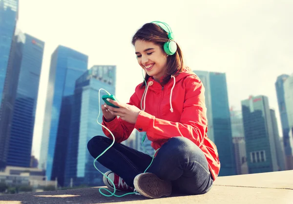 Щаслива молода жінка зі смартфоном та навушниками — стокове фото