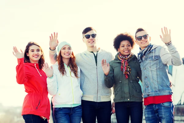 Happy teenage friends waving hands on city street — Stock Photo, Image