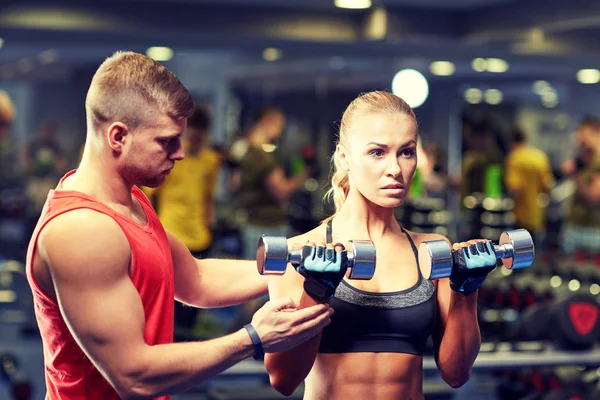 Jeune couple avec haltères flexion des muscles dans la salle de gym — Photo