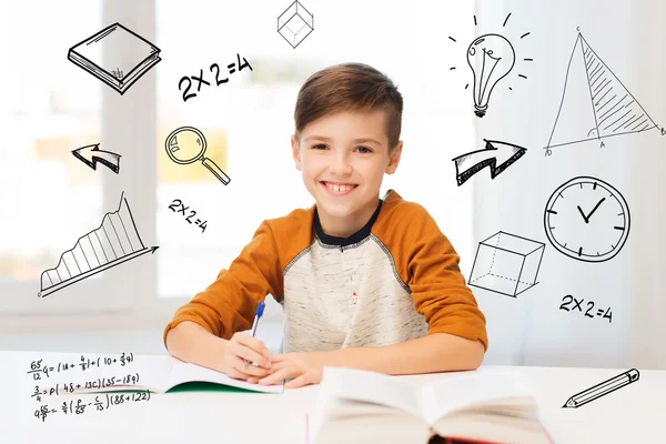 Glimlachende student jongen schrijven naar notebook thuis — Stockfoto