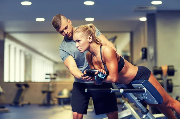 Kobieta z osobistym trenerem wyginanie mięśni w siłowni — Zdjęcie stockowe