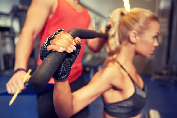 Hombres y mujeres flexionando los músculos en la máquina de gimnasio — Foto de Stock