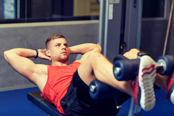 Hombre joven haciendo ejercicios abdominales en el gimnasio — Foto de Stock