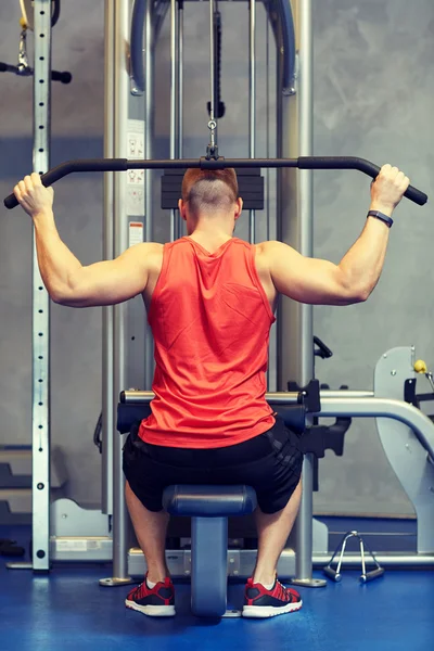 Homem flexionando músculos no ginásio máquina de cabo — Fotografia de Stock