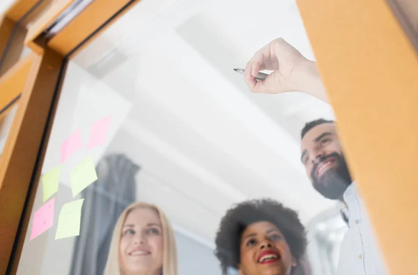 Glückliches kreatives Team, das auf leeres Büroglas schreibt — Stockfoto