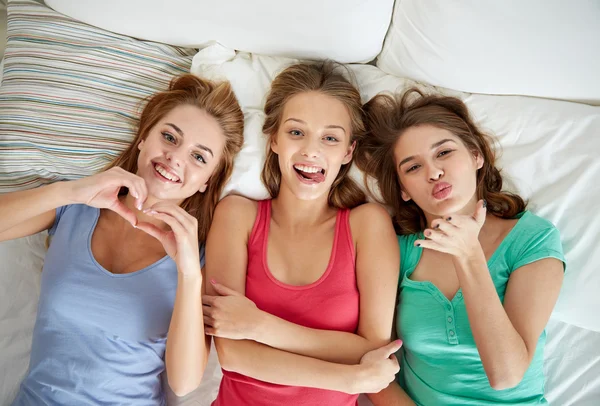 Счастливые молодые женщины в постели на домашней пижамной вечеринке — стоковое фото