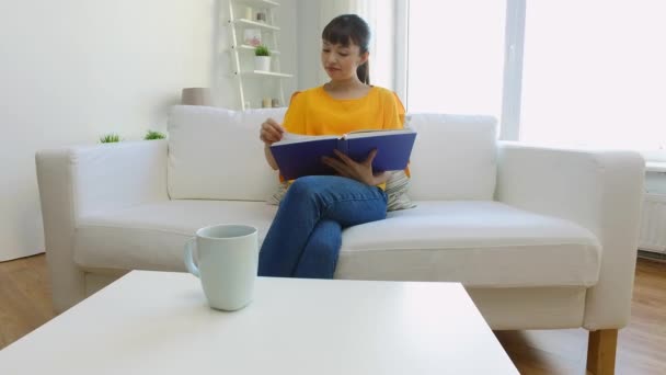 Sorrindo jovem asiático mulher ler livro em casa — Vídeo de Stock