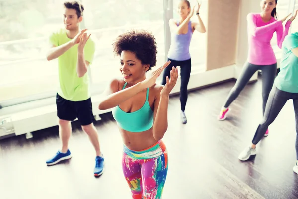 Group of smiling people dancing in gym or studio — Stock Photo, Image