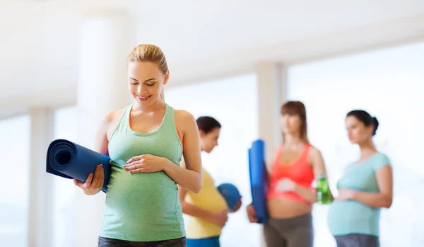 Mujer embarazada feliz con estera en el gimnasio —  Fotos de Stock