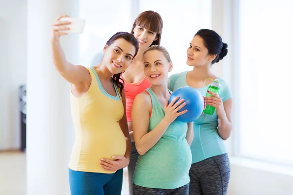 Mujeres embarazadas tomando selfie por teléfono inteligente en el gimnasio —  Fotos de Stock