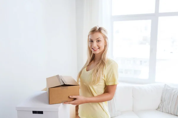 Giovane donna sorridente con scatola di cartone a casa — Foto Stock