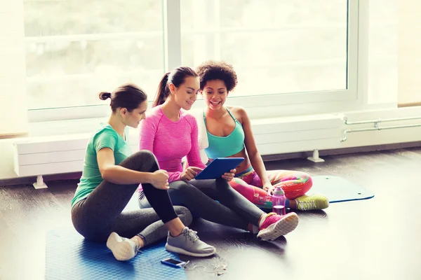 Groep gelukkige vrouwen met tablet pc in sportschool — Stockfoto