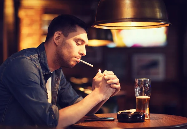 Mann trinkt Bier und raucht Zigarette an Bar — Stockfoto