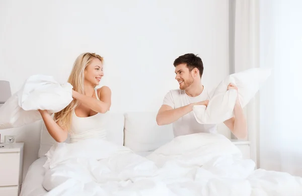 自宅のベッドで枕を持っている幸せなカップルの戦い — ストック写真