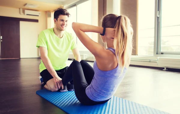 Žena s osobním trenérem dělá sit ups v tělocvičně — Stock fotografie